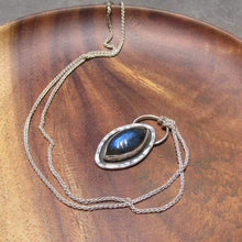 Load image into Gallery viewer, Our Daphne necklaces all feature a stunning deep blue marquise cut Labradorites. This royal hue is one of the most desired shades of the stone and looks stunning set in silver.  This Daphne is surrounded by a hammered silver halo and crowned with a large circular bail through which a shimmery silver chain is looped.