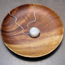 Load image into Gallery viewer, A fitting homage to the elegant and mysterious moon goddess Diana, this medallion style necklace features a weighty and luminous Moonstone cabochon bezel set and ringed with a wide band of solid silver. A sleek chain mounted directly to the edges of the pendant gives a clean finish and keeps the pendant centered.  A 16” chain ensures the pendant will lay comfortably just below your collarbones.