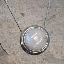 Load image into Gallery viewer, A fitting homage to the elegant and mysterious moon goddess Diana, this medallion style necklace features a weighty and luminous Moonstone cabochon bezel set and ringed with a wide band of solid silver. A sleek chain mounted directly to the edges of the pendant gives a clean finish and keeps the pendant centered.  A 16” chain ensures the pendant will lay comfortably just below your collarbones.