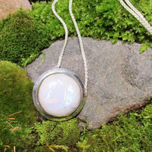Load image into Gallery viewer, A fitting homage to the elegant and mysterious moon goddess Diana, this medallion style necklace features a weighty and luminous Moonstone cabochon bezel set and ringed with a wide band of solid silver. A sleek chain mounted directly to the edges of the pendant gives a clean finish and keeps the pendant centered.  A 16” chain ensures the pendant will lay comfortably just below your collarbones.