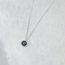 Load image into Gallery viewer, These sweet little pendant features an ethically sourced rosecut Teal Kyanite set in a simple recycled silver bezel. At 9mm wide, it is the perfect size for everyday wear while still adding a flash of sparkle to your look! This necklace pairs perfectly with the Luna Teal Kyanite Studs
