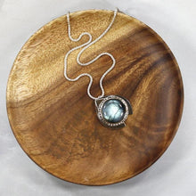 Load image into Gallery viewer, One part portal and one part shield talisman, this aqua blue Labradorite Deidra is all sleek elegance and high shine.     Details:  Solid sterling silver, partially recycled  Natural Labradorite cabochon  Pendant: 30 x 27mm  18” long Sterling Silver chain plus 2” Extender  Handmade s-hook clasp