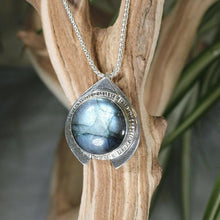 Load image into Gallery viewer, One part portal and one part shield talisman, this aqua blue Labradorite Deidra is all sleek elegance and high shine.     Details:  Solid sterling silver, partially recycled  Natural Labradorite cabochon  Pendant: 30 x 27mm  18” long Sterling Silver chain plus 2” Extender  Handmade s-hook clasp