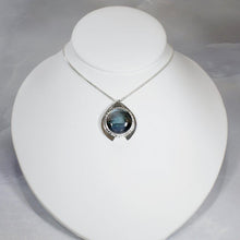 Load image into Gallery viewer, One part portal and one part shield talisman, this aqua blue Labradorite Deidra is all sleek elegance and high shine.     Details:  Solid sterling silver, partially recycled  Natural Labradorite cabochon  Pendant: 30 x 27mm  18” long Sterling Silver chain plus 2” Extender  Handmade s-hook clasp