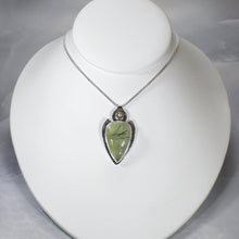 Load image into Gallery viewer, The Jeryn necklace is an absolute showstopper. Featuring a large translucent pear green Prehnite with black tourmaline inclusions, the spearhead shaped pendant is topped off with a luminous peachy green Labradorite set in a hand-texture bezel. A strong and elegant wheat chain balances the piece out and a 2” extension chain allows for neckline options.