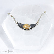Load image into Gallery viewer, A rosecut Rutilated Quartz rests on a silver crescent and is set off by antiqued oxidation on the backplate.  Details  Solid sterling silver, partially recycled  Rutilated Quartz  Pendant: 30mm x 12mm  19” long Sterling Silver chain plus 2" extension  Lobster-claw clasp