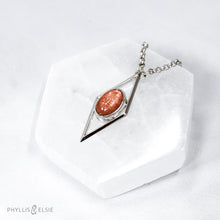Load image into Gallery viewer, A rich orange oval Sunstone is centered in a diamond frame of polished silver. Beveled edges catch the light and highlight the stone floating in the center.  Details  Solid sterling silver, partially recycled  Sunstone  Pendant: 17mm x 41mm  18" Sterling chain plus 2" extension   Lobster claw clasp