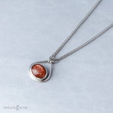Load image into Gallery viewer, A shimmering orange Sunstone set in a silver bezel and nestled in an elegant and minimalist teardrop halo.   Solid sterling silver, partially recycled  Sunstone  Pendant 17mm x 20mm 16” long Sterling Silver chain plus 2" Extension  Lobster claw clasp