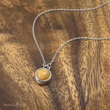 Load image into Gallery viewer, This 9mm Luna necklace features a beautiful orange Ethiopian Opal set simply in a smooth silver bezel. A a diamond cut chain adds a subtle sparkle to complete the clean, classic look you will find yourself wearing over and over.  Details:  Solid sterling silver, partially recycled  Ethiopian Opal  Pendant: 9mm  16” long Sterling Silver chain   Lobster-claw clasp