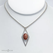Load image into Gallery viewer, A rich orange oval Sunstone is centered in a diamond frame of polished silver. Beveled edges catch the light and highlight the stone floating in the center.  Details:  Solid sterling silver, partially recycled  Sunstone  Pendant: 17mm x 41mm  18" Sterling chain plus 2" extension   Lobster claw clasp