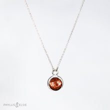 Load image into Gallery viewer, This 10mm Luna necklace features a beautiful rust colored Sunstone set simply in a smooth silver bezel. A slim oval chain completes the clean, classic look you will find yourself wearing over and over.  Details  Solid sterling silver, partially recycled  Sunstone  Pendant: 10mm  16” long Sterling Silver chain   Lobster-claw clasp