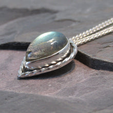 Load image into Gallery viewer, This Stella necklace features a glowing, smooth sage-green Labradorite teardop cabochon that shows glimpses of peach and aqua in bright light. Surrounded with a slightly-offset twisted halo, this pendant stands out despite its small size and soft colors.