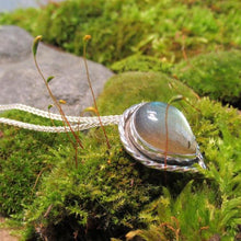 Load image into Gallery viewer, This Stella necklace features a glowing, smooth sage-green Labradorite teardop cabochon that shows glimpses of peach and aqua in bright light. Surrounded with a slightly-offset twisted halo, this pendant stands out despite its small size and soft colors.