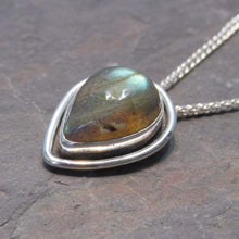 Load image into Gallery viewer, This Stella necklace features an iridescent aqua to amber Labradorite teardop cabochon surrounded by a classic halo of polished round wire. A hidden bail lets the pendant float on the chain with no visual clutter. Simultaneously minimal and unusual, this Stella necklace is the perfect finishing touch to a wide range of looks.