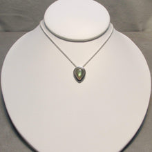 Load image into Gallery viewer, This Stella necklace features an iridescent aqua to amber Labradorite teardop cabochon surrounded by a classic halo of polished round wire. A hidden bail lets the pendant float on the chain with no visual clutter. Simultaneously minimal and unusual, this Stella necklace is the perfect finishing touch to a wide range of looks.