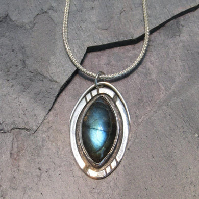 Our Daphne necklaces all feature a stunning deep blue marquise cut Labradorites. This royal hue is one of the most desired shades of the stone and looks stunning set in silver.  This Daphne  is set in a sleek shadowbox with hand-carved notches that reference an Art-Deco aesthetic. A simple arched bail provides a sleek connection to a smooth, round, foxtail chain.
