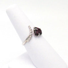 Load image into Gallery viewer, A juicy polished natural Garnet is perched in a .925 Sterling Silver three-prong setting on an asymmetrical ring band studded with silver pebbles. 
