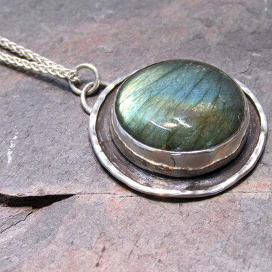 This Jaida necklace has an earthy, organic feel with its blue-green Labradorite centered in an antiqued shadowbox framed by a hand-textured halo. The sleek silver wheat chain lets the pendant steal the show while still providing elegance and strength.