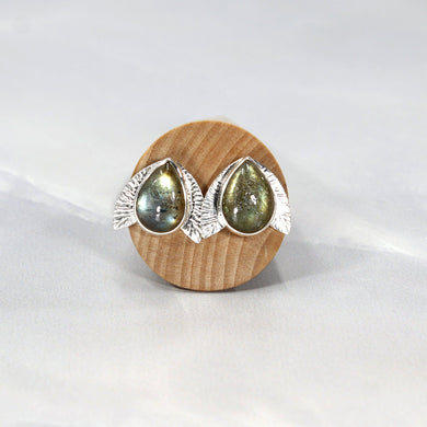 This playful pair of stud earrings features large glowing green Labradorite teardop cabochons flanked by hand-textured silver wings.  