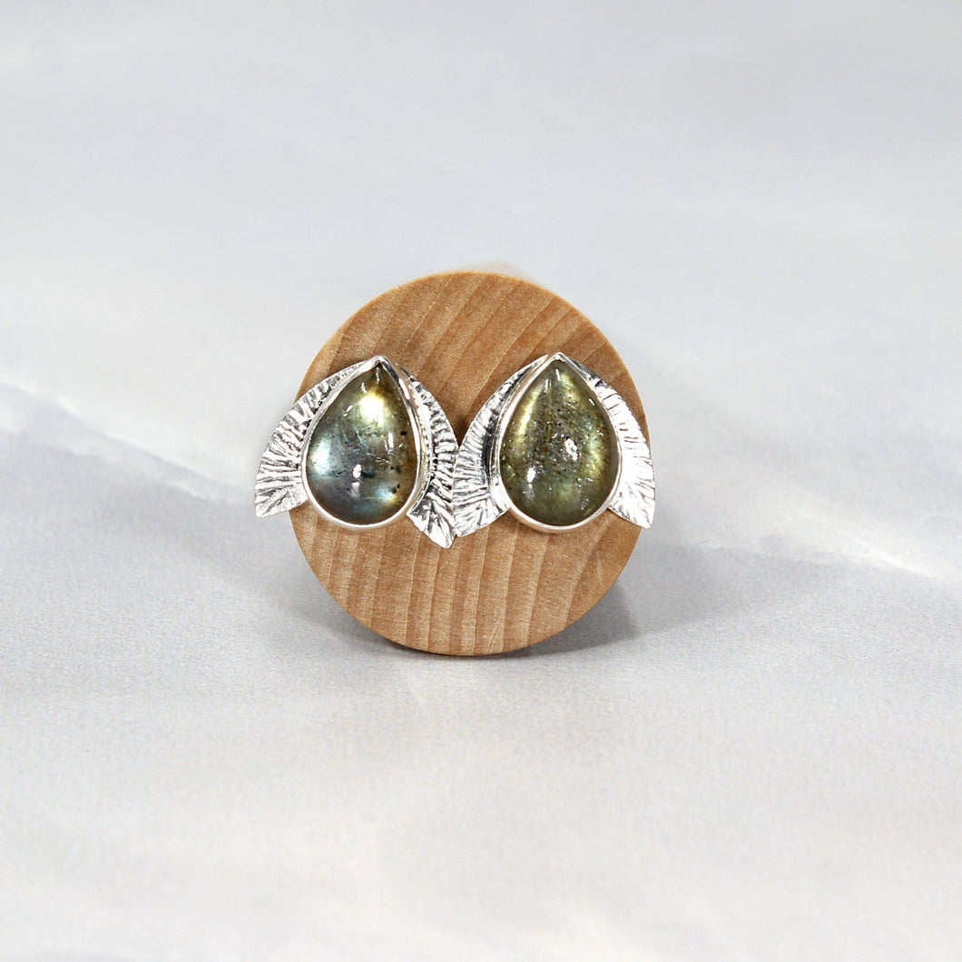 This playful pair of stud earrings features large glowing green Labradorite teardop cabochons flanked by hand-textured silver wings.  