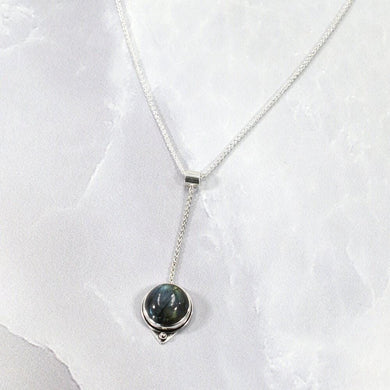 With its exceptional deep blue Labradorite, Taylor carries a mystical hint of midnight. Dangling from a wheat chain and accented by a thin silver band and tiny silver pebble, this necklace is delicate but eye-catching.