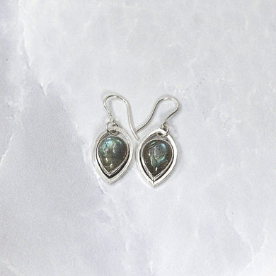 These lovely dangle earrings feature soft blue-grey labradorite teardrops nestled into Sterling Silver leaf hoops. A double loop connection gives these gems lots of movement to catch the light.