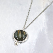 Load image into Gallery viewer, This gorgeous Valarie necklace will be the center of your outfit. A large deep green labradorite with flashy golden stripes is surrounded by a peaked ring of silver and accented by a tiny labradorite set on a hand-textured backer. Delicately hand-cut vine patterns on the back give this piece an extra custom feel.
