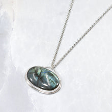 Load image into Gallery viewer, The Johnna necklace is minimal in form and maximal in impact. A delicate peaked silver band holds this large, flashy, aqua Labradorite in its rightful place, front and center. With plenty of color this piece will add glam to any look, while its soft turquoise and denim hues will be easy to style with your wardrobe staples.
