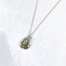 Load image into Gallery viewer, Tara evokes the new life of a seed just sprouted. A green-gold Labradorite is nestled in a tapered silver swirl and topped with a tiny dewdrop Labradorite.
