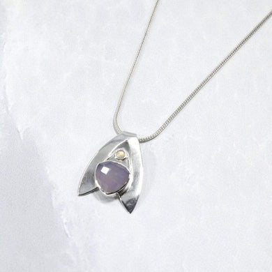 Sleek and polished, the Lilian features a dreamy checker cut Lilac Chalcedony crowned by a soft peachy drop of Labradorite. Smooth wings curve back to seamlessly form a bail that slides along a finely woven foxtail chain.