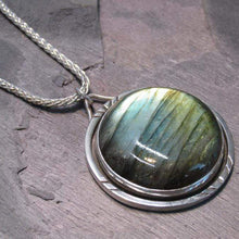 Load image into Gallery viewer, With a stunning streaked green and blue round Labradorite, the Rochelle necklace provides a lush focal point for your look. Ringed with a square-wire halo with delicate hand-carved notches and an unusual peaked bail, Rochelle is sure to be a well-loved addition to your collection.
