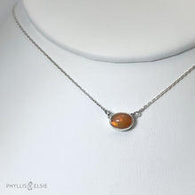 Load image into Gallery viewer, Evie brings the perfect tiny highlight to your look. The lovely Ethiopian Opal shows flashes of hot pink, orange, and green in a soft orange base. It and is nestled in a delicate diamond-cut sterling silver chain for extra sparkle.  Solid sterling silver, partially recycled  Ethiopian Opal   Pendant 10mm X 6mm  16” long Sterling Silver chain  Lobster claw clasp
