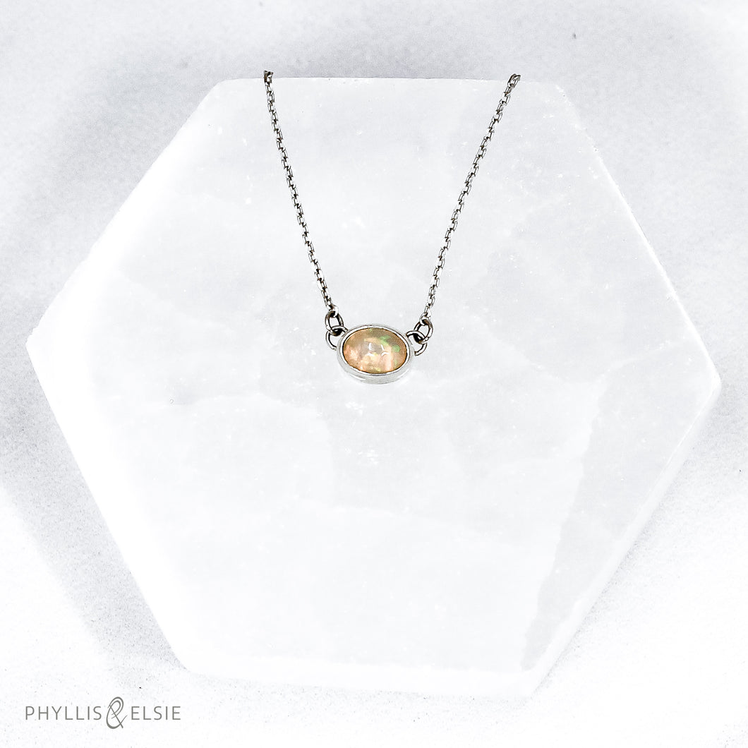 Evie brings the perfect tiny highlight to your look. The lovely Ethiopian Opal shows flashes of peach, green, and yellow and is nestled in a delicate diamond-cut sterling silver chain for extra sparkle.  Details  Solid sterling silver, partially recycled  Ethiopian Opal   Pendant 10mm X 6mm  16” long Sterling Silver chain  Lobster claw clasp