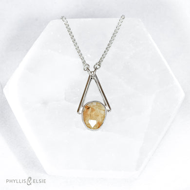 Rosecut Quartz with golden hued crystalline inclusions set in a silver bezel and suspended in an airy frame  Details:  Solid sterling silver, partially recycled  Rutilated Quartz  Pendant: 13mm x 26mm  16” long Sterling Silver chain plus 2” Extender  Lobster-claw clasp