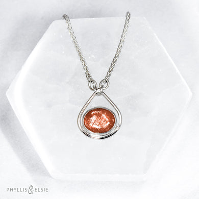 A shimmering orange Sunstone set in a silver bezel and nestled in an elegant and minimalist teardrop halo.   Details  Solid sterling silver, partially recycled  Sunstone  Pendant 17mm x 20mm  16” long Sterling Silver chain plus 2