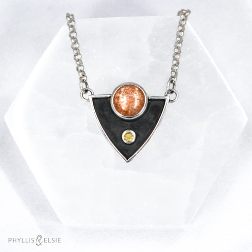 A shimmering Sunstone rises through the thick silver frame of its shadowbox. A faceted golden Topaz adds even more color and sparkle to this striking pendant.  Details  Solid sterling silver, partially recycled  Sunstone & Golden Topaz  Pendant: 28mm x 23mm  18” long Sterling Silver chain plus 2