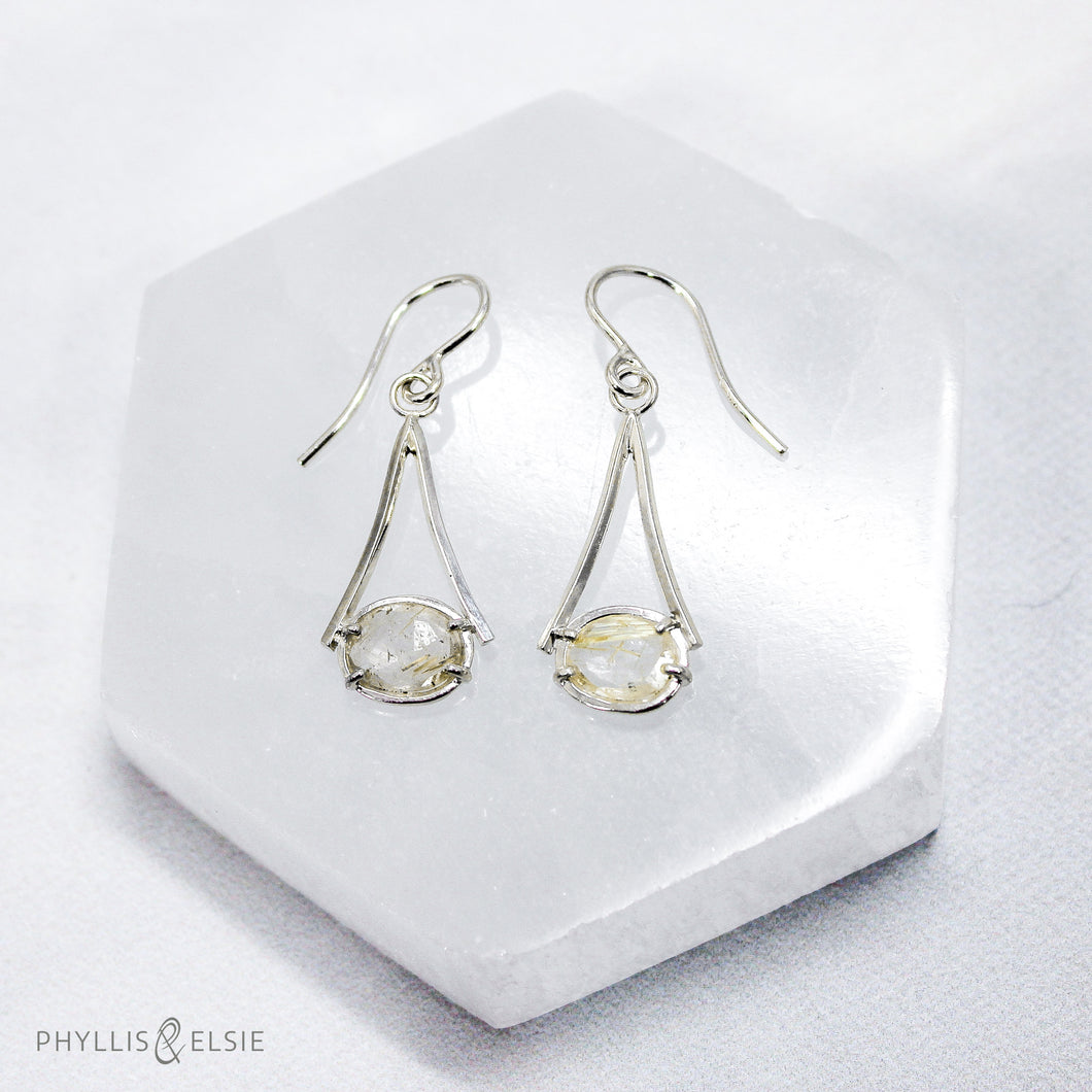 Light and airy Sterling Silver dangles set with Rutilated Quartz with golden inclusions for just a touch of sparkle.  Details:  Solid sterling silver, partially recycled  Rutilated Quartz  Earring faces: 12mm x 25mm  Sterling silver ear hooks