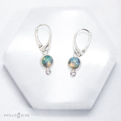 Sweet dewdrops of Ethiopian Opals glow with shades of blue, green, and peach. White Sapphires at an extra touch of sparkle and elegant lever-back ear hooks keep your earrings secure with extra style.  Details  Solid sterling silver, partially recycled  Ethiopian Opal, White Sapphire  Earring face: 8mm x 15mm  Sterling lever-back hooks