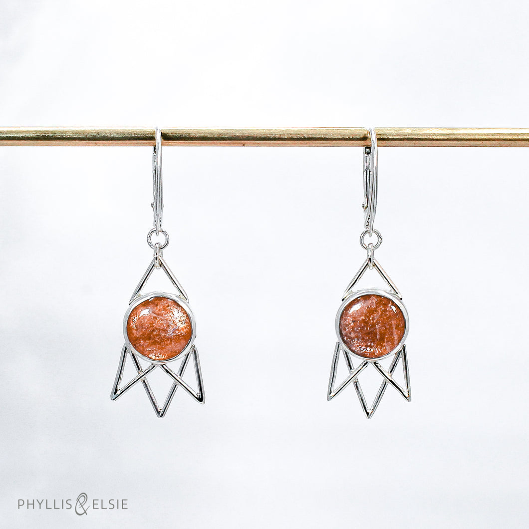 Shimmering Sunstone cabochons flanked by silver openwork rays and suspended from elegant lever-back ear hooks  Solid sterling silver, partially recycled  Sunstone  Earring faces: 15mm x 30mm  Sterling silver ear hooks