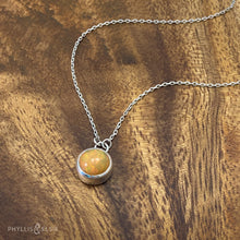 Load image into Gallery viewer, This 9mm Luna necklace features a beautiful orange Ethiopian Opal set simply in a smooth silver bezel. A a diamond cut chain adds a subtle sparkle to complete the clean, classic look you will find yourself wearing over and over.  Details:  Solid sterling silver, partially recycled  Ethiopian Opal  Pendant: 9mm  16” long Sterling Silver chain   Lobster-claw clasp
