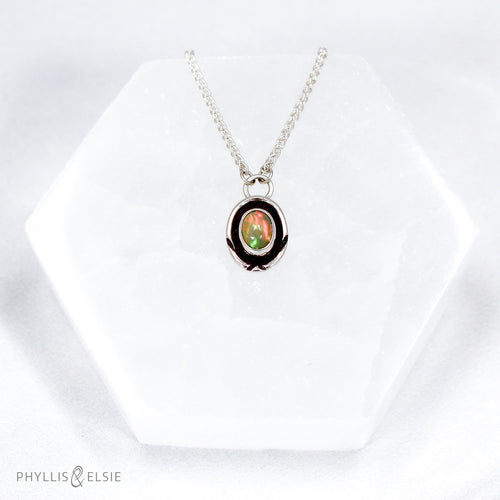 A super flashy Ethiopian Opal wrapped in a silver bezel is framed by a slim patinated shadowbox and hand carved details.   Details:  Solid sterling silver, partially recycled  Ethiopian Opal  Pendant: 10mm x 16mm 16” long Sterling Silver chain plus 2