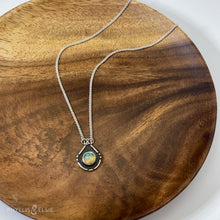 Load image into Gallery viewer, A luminous Ethiopian Opal wrapped in a silver bezel is framed by a geometric shadowbox and hand carved details.   Details:  Solid sterling silver, partially recycled  Ethiopian Opal  Pendant: 14mm x 18mm  16” long Sterling Silver chain plus 2&quot; extension  Lobster-claw clasp
