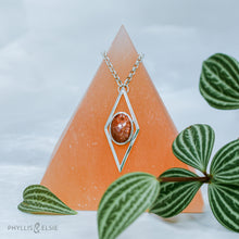 Load image into Gallery viewer, A rich orange oval Sunstone is centered in a diamond frame of polished silver. Beveled edges catch the light and highlight the stone floating in the center.  Details:  Solid sterling silver, partially recycled  Sunstone  Pendant: 17mm x 41mm  18&quot; Sterling chain plus 2&quot; extension   Lobster claw clasp
