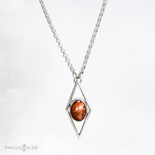 Load image into Gallery viewer, A rich orange oval Sunstone is centered in a diamond frame of polished silver. Beveled edges catch the light and highlight the stone floating in the center.  Details  Solid sterling silver, partially recycled  Sunstone  Pendant: 17mm x 41mm  18&quot; Sterling chain plus 2&quot; extension   Lobster claw clasp
