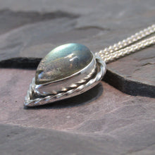 Load image into Gallery viewer, This Stella necklace features a glowing, smooth sage-green Labradorite teardop cabochon that shows glimpses of peach and aqua in bright light. Surrounded with a slightly-offset twisted halo, this pendant stands out despite its small size and soft colors.
