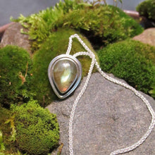 Load image into Gallery viewer, This Stella necklace features an iridescent aqua to amber Labradorite teardop cabochon surrounded by a classic halo of polished round wire. A hidden bail lets the pendant float on the chain with no visual clutter. Simultaneously minimal and unusual, this Stella necklace is the perfect finishing touch to a wide range of looks.
